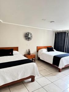 a bedroom with two beds and a clock on the wall at HOTEL FLAMINGOS DE CIUDAD GUZMAN in Ciudad Guzmán