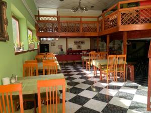a restaurant with wooden tables and chairs and a checkered floor at Várfal Panzió és Wellness in Pécs