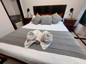 a bedroom with a bed with towels on it at Pousada Casa da Pedra in Búzios