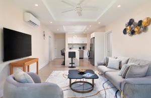 a living room with two couches and a flat screen tv at Modern 2BR Beachside Haven Ground Floor and Pool in Saint Peter