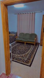 a living room with a green couch and a rug at Lovely hotel in Al Qābūţī