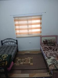 two beds in a small room with a window at Lovely hotel in Al Qābūţī +3 photos