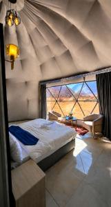 a bedroom with a bed and a large window at Olivia Rum Luxury Bubbles & Jeep Tours in Wadi Rum