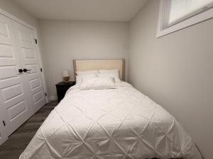 a white bed in a room with a door at Eden Secret YYC in Calgary