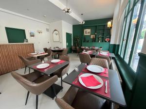a restaurant with tables and chairs and green walls at LOGIS HOTEL - Le Petit Bellon in Senlis