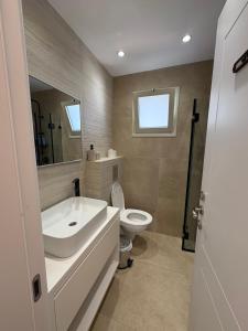 a bathroom with a white sink and a toilet at Mykonos unite in Rishon LeẔiyyon +6 photos