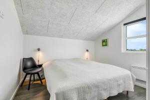 a bedroom with a white bed and a black chair at C11349-Tarm-Stikkelsbaervej-43 in Tarm