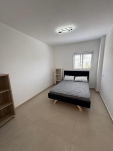 a bedroom with a bed in a white room at Mykonos unite in Rishon LeẔiyyon