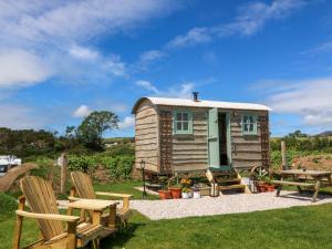ein kleines Haus mit Picknicktisch und Bänken in der Unterkunft Cwt Bugail in Pwllheli