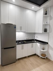a kitchen with white cabinets and a refrigerator at Cozy apartment in Angisa