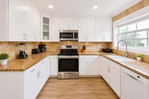 a kitchen with white cabinets and stainless steel appliances at The Golfstream Dunes Villa in Hallandale Beach