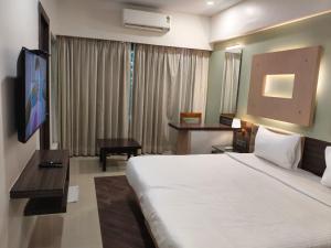a hotel room with a large bed and a television at Hotel Mumbai House Thane in Thane