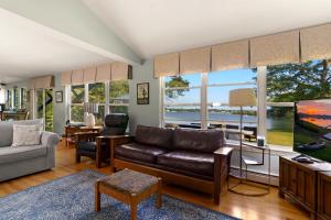 a living room with a couch and chairs and windows at Waterfront Estate w Hot Tub, Dock & Kayaks in Stonington