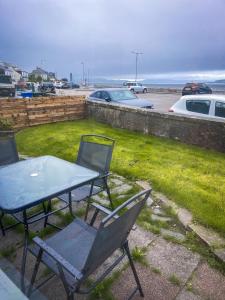 a table and chairs on a patio with the ocean at Vistamar Dunoon in Dunoon
