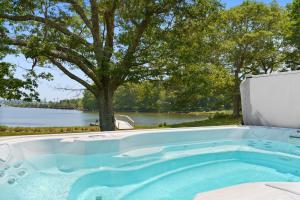 a jacuzzi tub with a tree and a lake at Waterfront Estate w Hot Tub, Dock & Kayaks in Stonington