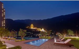 a pool with two lounge chairs and a city at night at Studio 4pax SunshineKekloksiView in Ayer Itam