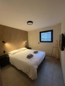 a bedroom with a large white bed and a window at Les Loges de Sainte Anne in Saint-Michel-de-Maurienne
