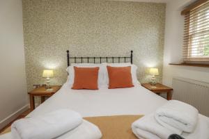 a bedroom with a bed with orange pillows and two chairs at 15 Boscaswell Downs in Penzance