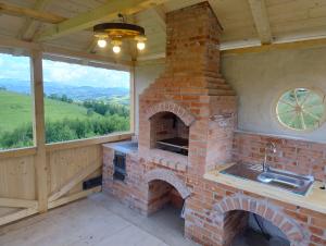 an outdoor kitchen with a brick oven and a window at Casa Vlădușca in Peştera