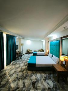 a hotel room with a large bed and a desk at Hotel Ararat in Erbil