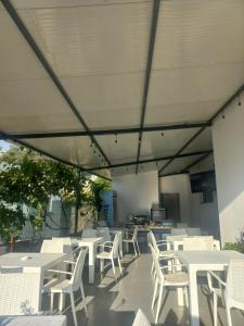 a patio with white tables and white chairs at Vila Familjare Memushi in Ksamil