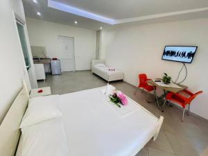 a room with two beds and a table and a tv at Donald Hotel in Vlorë