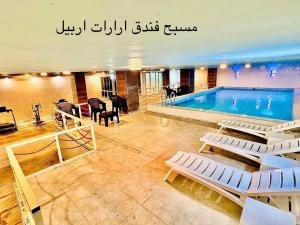 a building with a pool and chairs at Hotel Ararat in Erbil