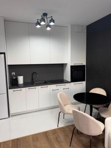 a kitchen with white cabinets and a table and chairs at MC Residence Łomża in Łomża