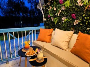 a couch sitting on a balcony with a table with fruit at Tropical Chic Studio - Marina View - Swimming Pool in Les Trois-Îlets