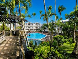 a view of a resort swimming pool with palm trees at Tropical Chic Studio - Marina View - Swimming Pool in Les Trois-Îlets