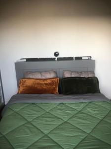 a bedroom with a bed with green sheets and pillows at Near Paris in Ris-Orangis