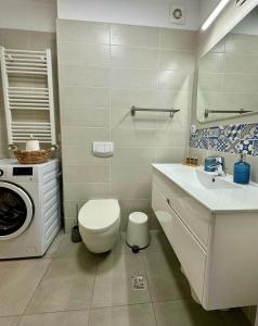 a bathroom with a toilet and a sink and a washing machine at MAYA Studio-Onix Blue with Private Parking, Mamaia Nord in Mamaia Sat/Năvodari +15 photos