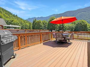 a wooden deck with a table and an umbrella at Lake Sutherland Chalet Tiny home with lake access in Port Angeles