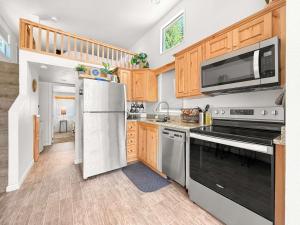 a kitchen with wooden cabinets and stainless steel appliances at Lake Sutherland Chalet Tiny home with lake access in Port Angeles +17 photos