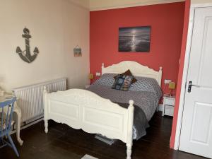 a bedroom with a white bed and a red wall at Henry's On The Prom in Great Yarmouth