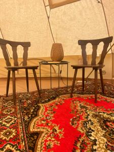 two chairs and a table in a room with a rug at KEMPINGS Kareļi in Saraiķi +31 photos