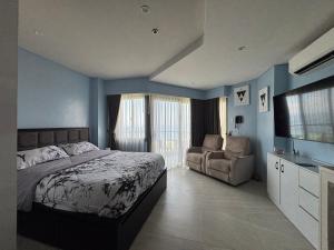 a bedroom with a bed and a chair and a television at Ocean View Corner Studio Private Balcony Tambuli Tower F in Maribago