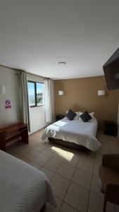 a bedroom with a bed and a tv in it at Hosteria Puerta del Sol in Caldera +16 photos