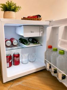 an open refrigerator filled with bottles and cans of soda at Hotel Via Center in Divino