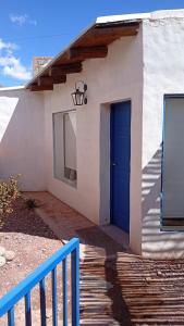 a white house with a blue door and a fence at Cabañas don Julio in Maimará