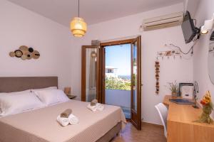 a bedroom with a bed and a desk and a window at Flo Guest House in Sifnos
