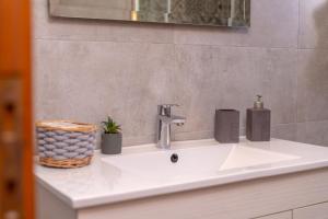 a bathroom sink with a faucet and a basket on it at Flo Guest House in Sifnos +31 photos
