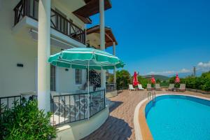 a house with a swimming pool and an umbrella at HENNA VILLA in Fethiye