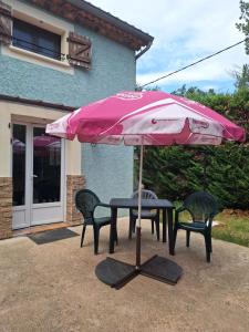 a table and chairs under a pink umbrella at Les cyprès in Lagorce