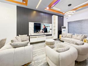 a living room with white furniture and a flat screen tv at Domina Apartment in Kubwa