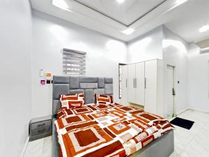 a bedroom with a bed with orange and white comforter at Domina Apartment in Kubwa