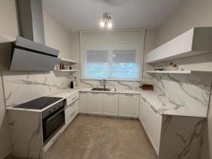 a white kitchen with marble counter tops and a sink at Valamar Priam Villa D11 in Hamallë