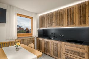 a kitchen with wooden cabinets and a table and a window at Ferienwohnung Mair am Bach in Brunico
