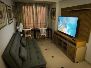 a living room with a couch and a flat screen tv at VM Flats Guarulhos Aeroporto in Guarulhos