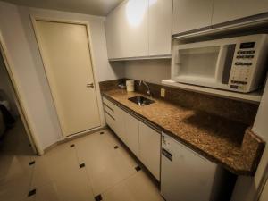 a small kitchen with a sink and a microwave at VM Flats Guarulhos Aeroporto in Guarulhos